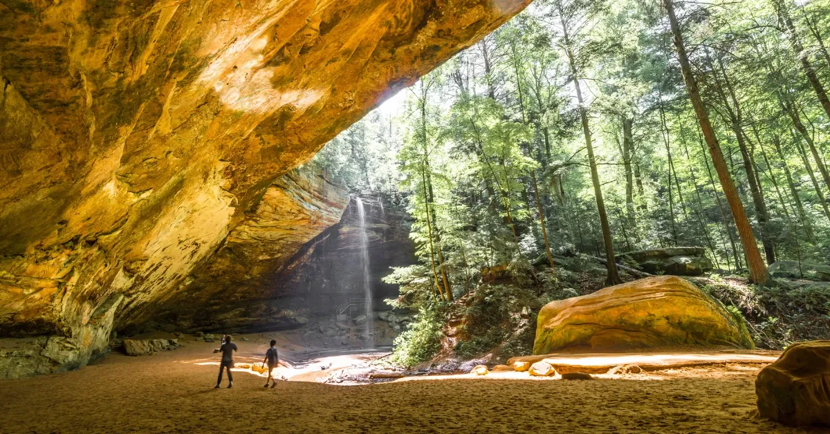 Hikers below the sandstone overhang and waterfall at Ash Cave in Hocking Hills State Park near Athens, Ohio