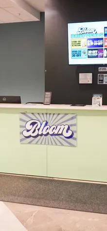 Check-in desk at the Bloom dispensary in Athens, Ohio, with a daily deals screen and two ATMs.