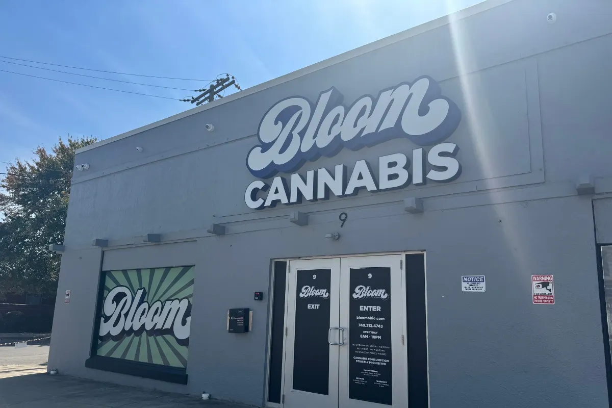 Exterior of the Bloom Cannabis dispensary in Athens, Ohio, with the Bloom logo on the building and front entrance on a sunny day