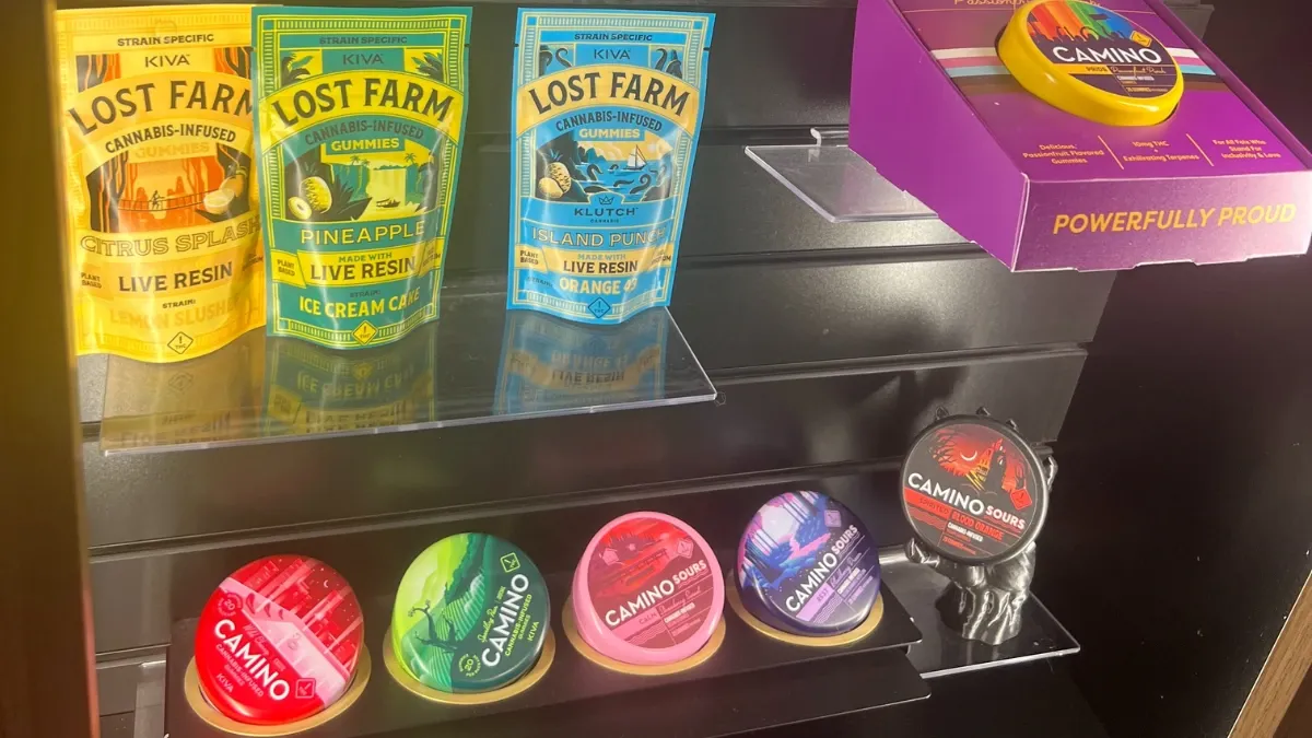 Lost Farm gummy pouches and Camino gummy tins on an acrylic display shelf at the dispensary counter