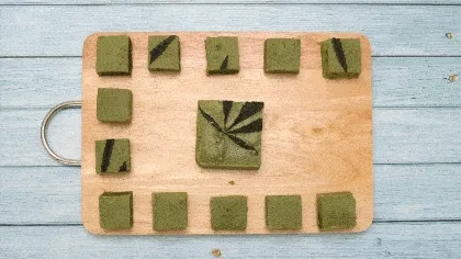 Green cannabis edible cut into small square portions on a wooden cutting board