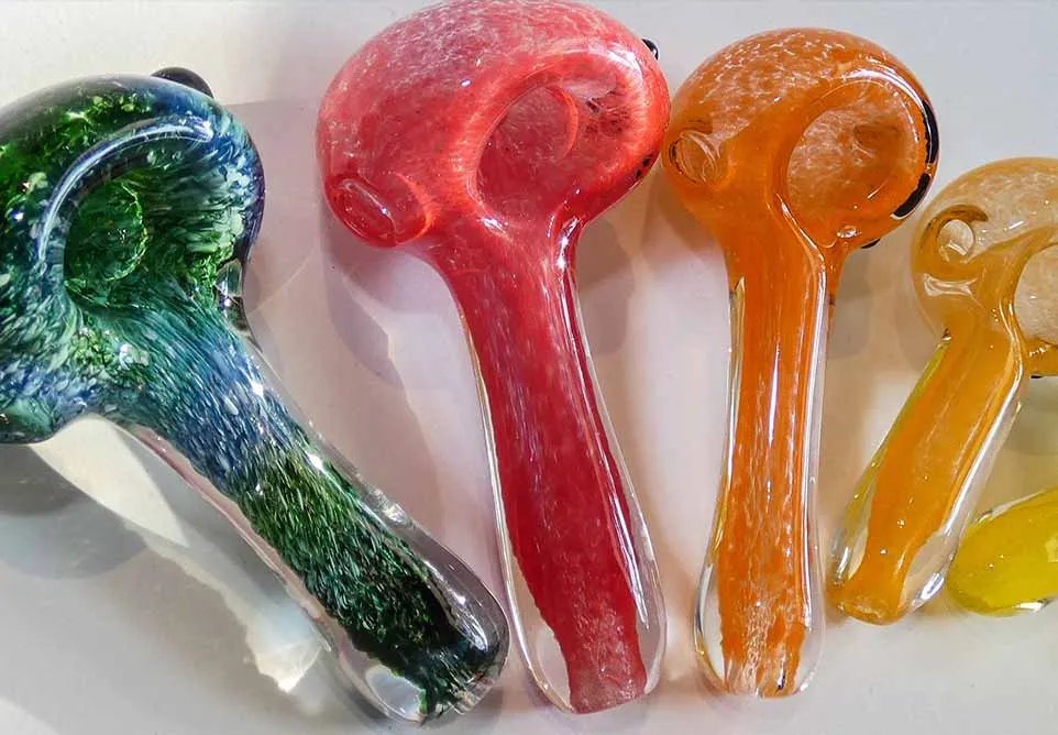 Row of colorful glass hand pipes in green, red, orange and yellow fumed glass