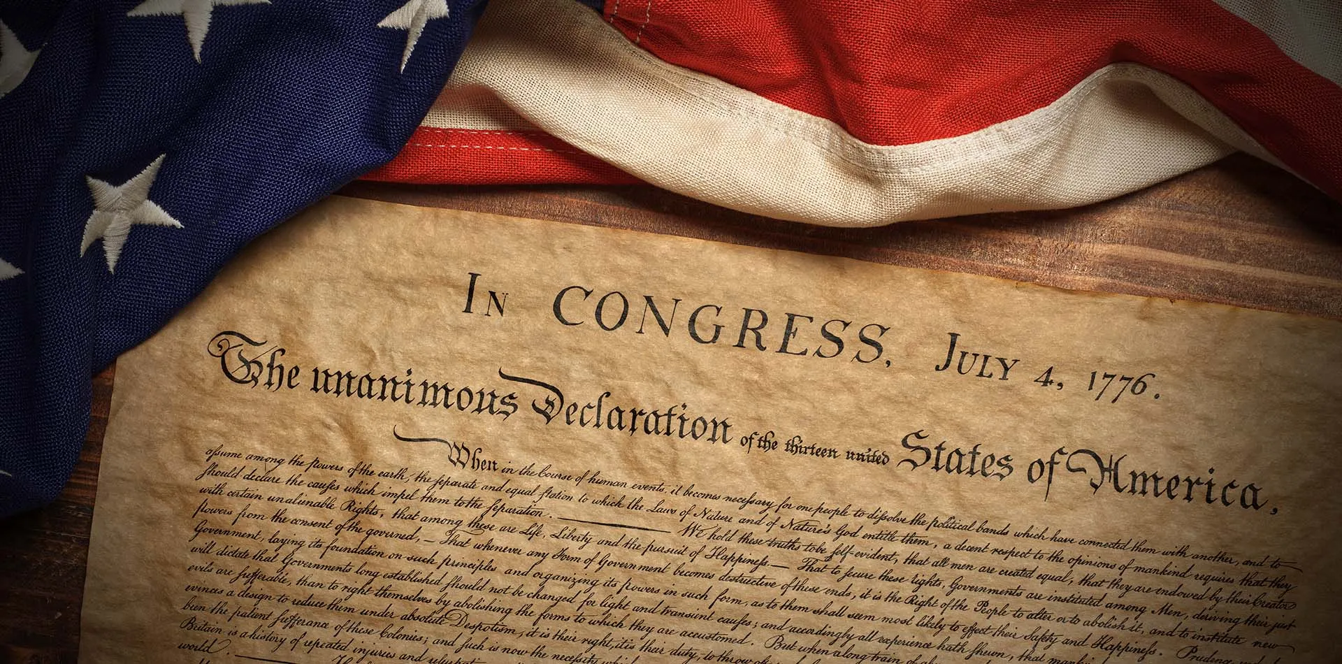 Aged parchment of the Declaration of Independence draped with an American flag