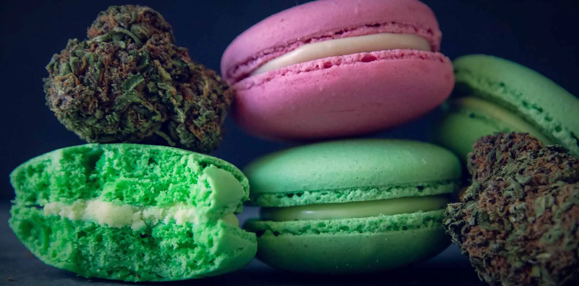 Green and pink macarons stacked beside dried cannabis buds