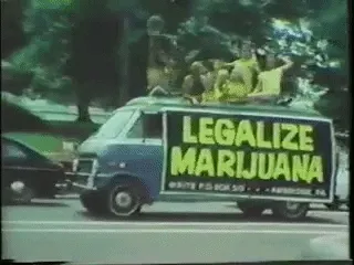 Vintage footage of people riding on top of a van with a Legalize Marijuana banner