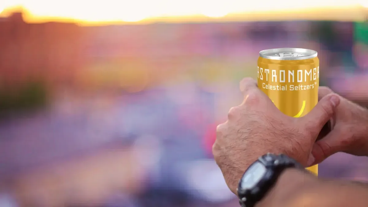 Man holding a can of THC-infused seltzer outdoors at sunset