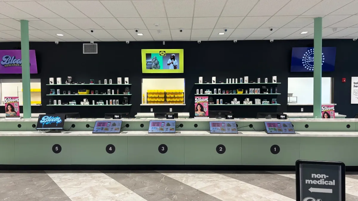 Long sales counter with product display screens and shelves inside the Bloom Massillon dispensary in Stark County, Ohio