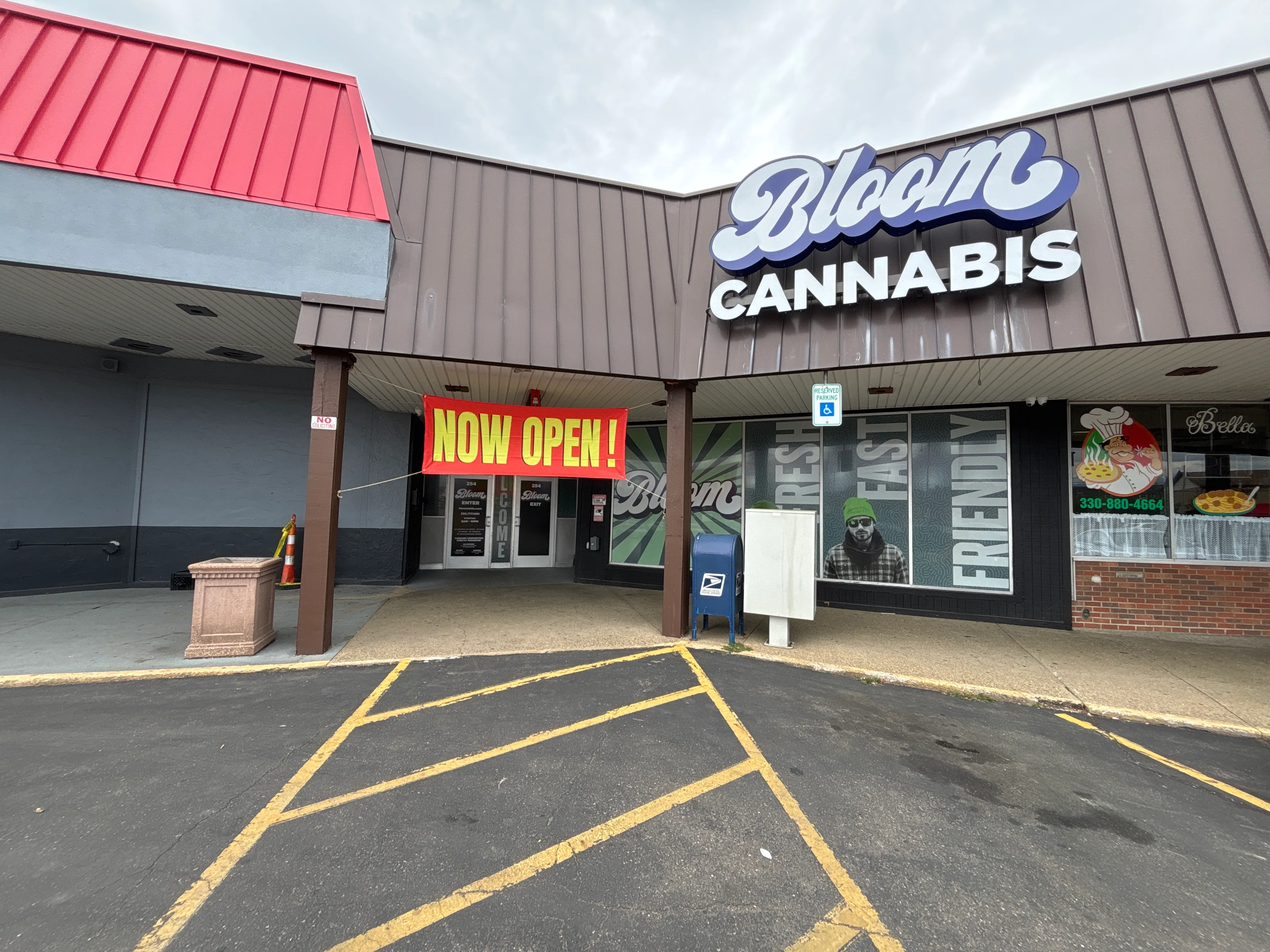 Bloom Cannabis dispensary storefront in Towne Plaza on Federal Avenue NW in Massillon, Ohio, with the Bloom Cannabis sign, a lit Now Open sign and free parking out front.
