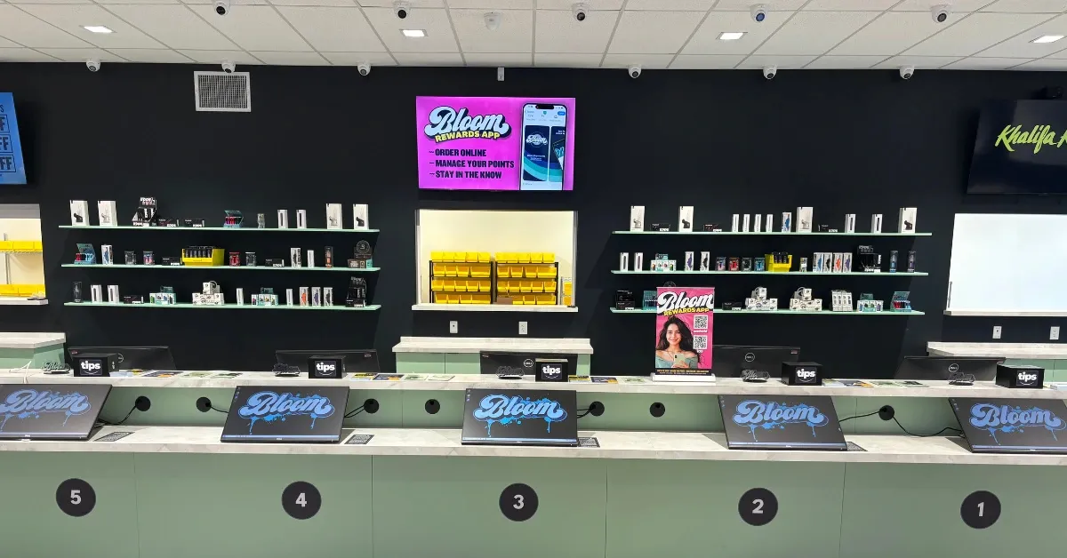 Modern Bloom dispensary interior with a long product wall and numbered self-order kiosks