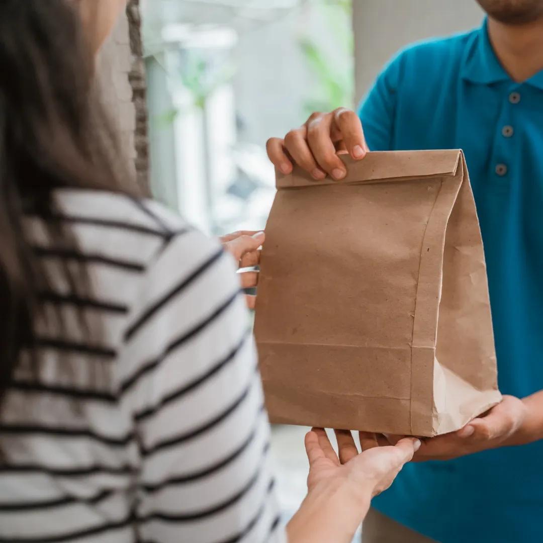 A paper bag being handed over at a front door, illustrating future medical cannabis delivery under Ohio Senate Bill 56