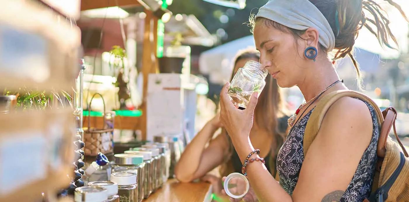 Woman smelling cannabis from a jar at a dispensary counter