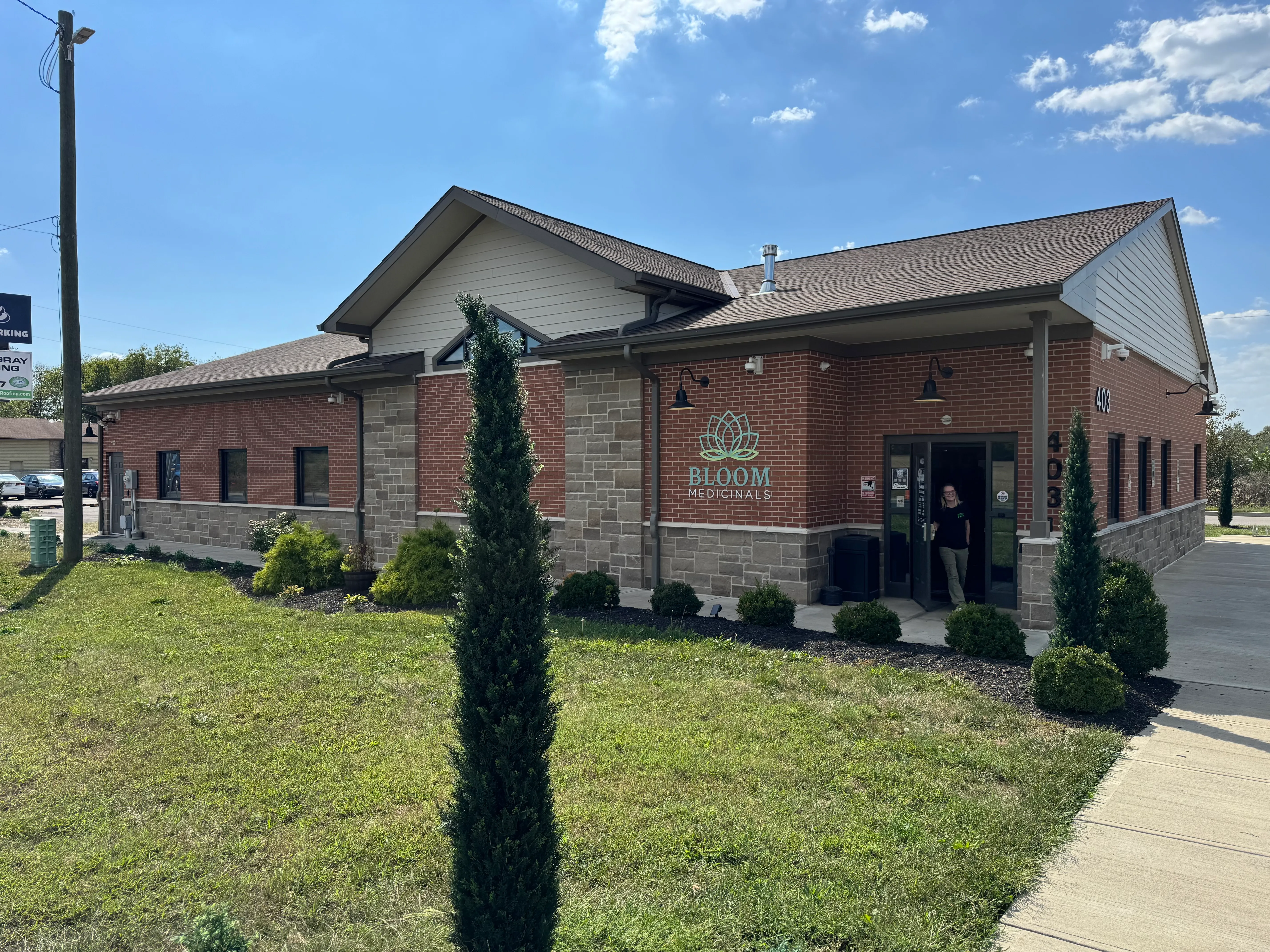 Bloom Cannabis dispensary on South Main Street (US-127) in Seven Mile, Ohio — a brick and stone building with a landscaped front lawn and main entrance.