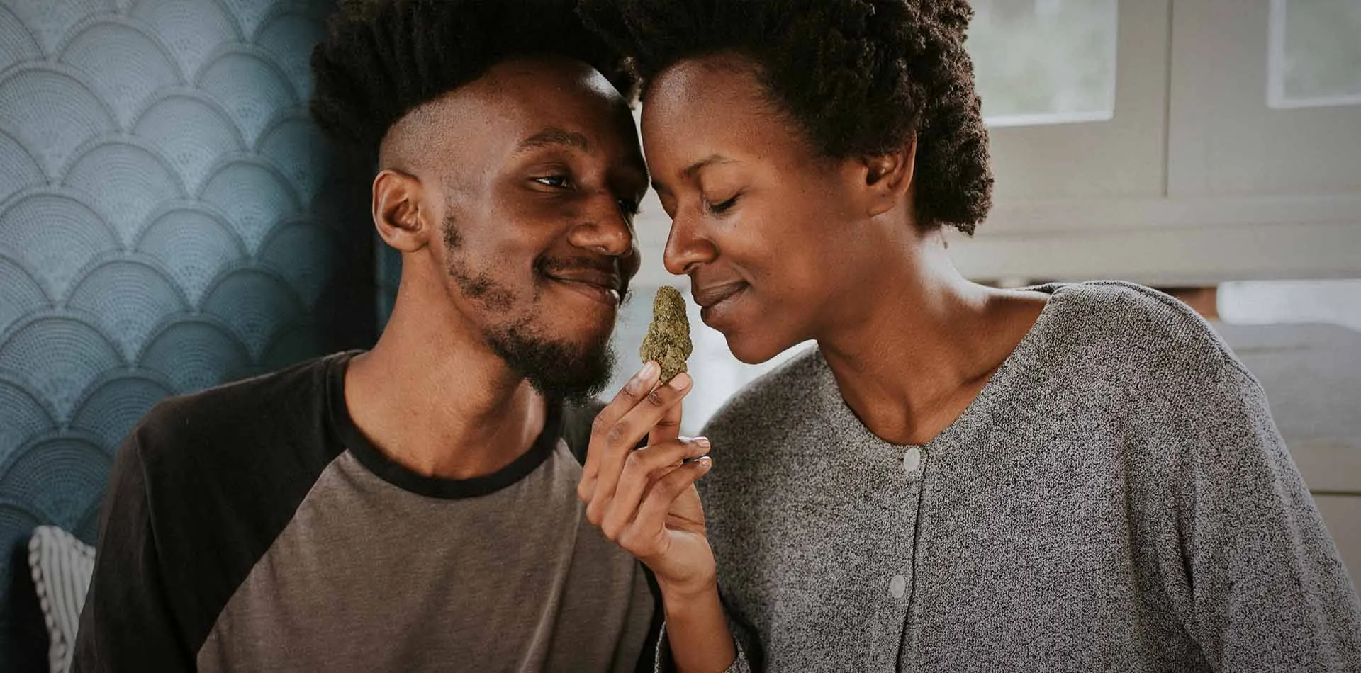 Smiling couple leaning in together to smell a cannabis bud