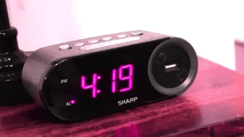 Digital alarm clock on a nightstand flipping from 4:19 to 4:20