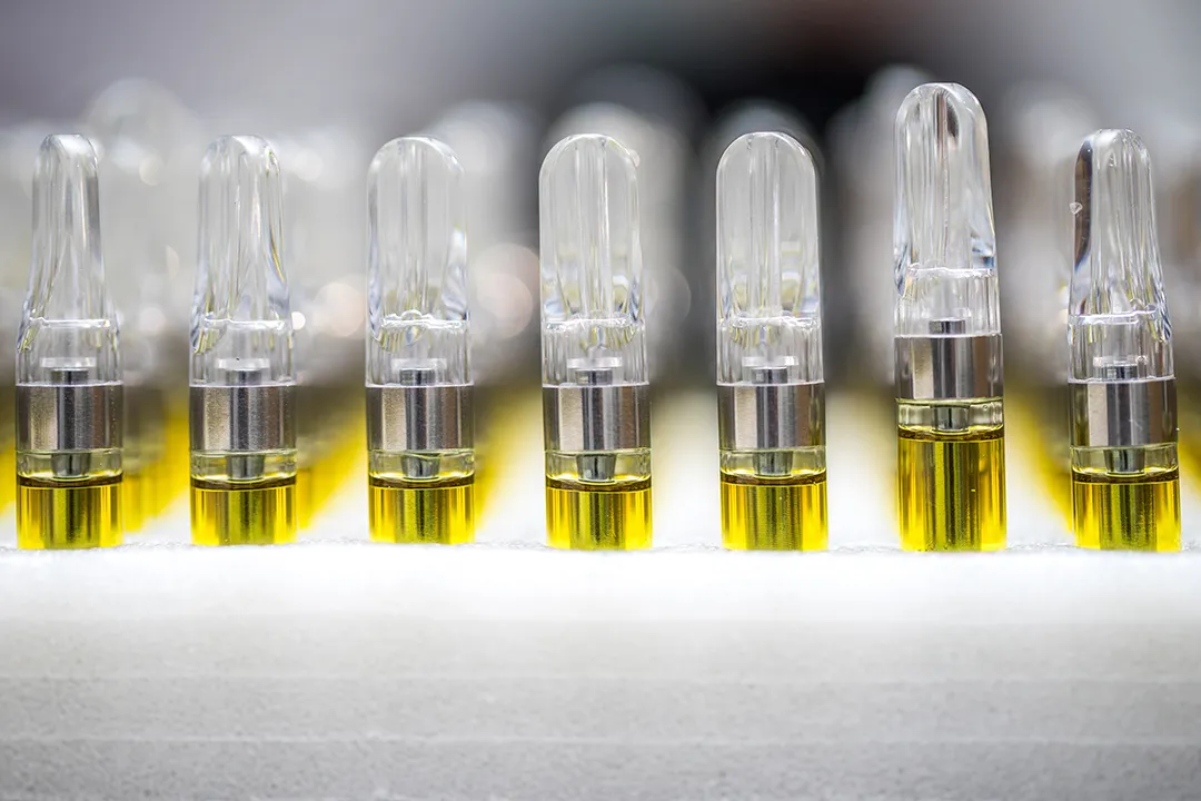 Row of glass cannabis vape cartridges filled with golden oil, each with a small air gap at the top