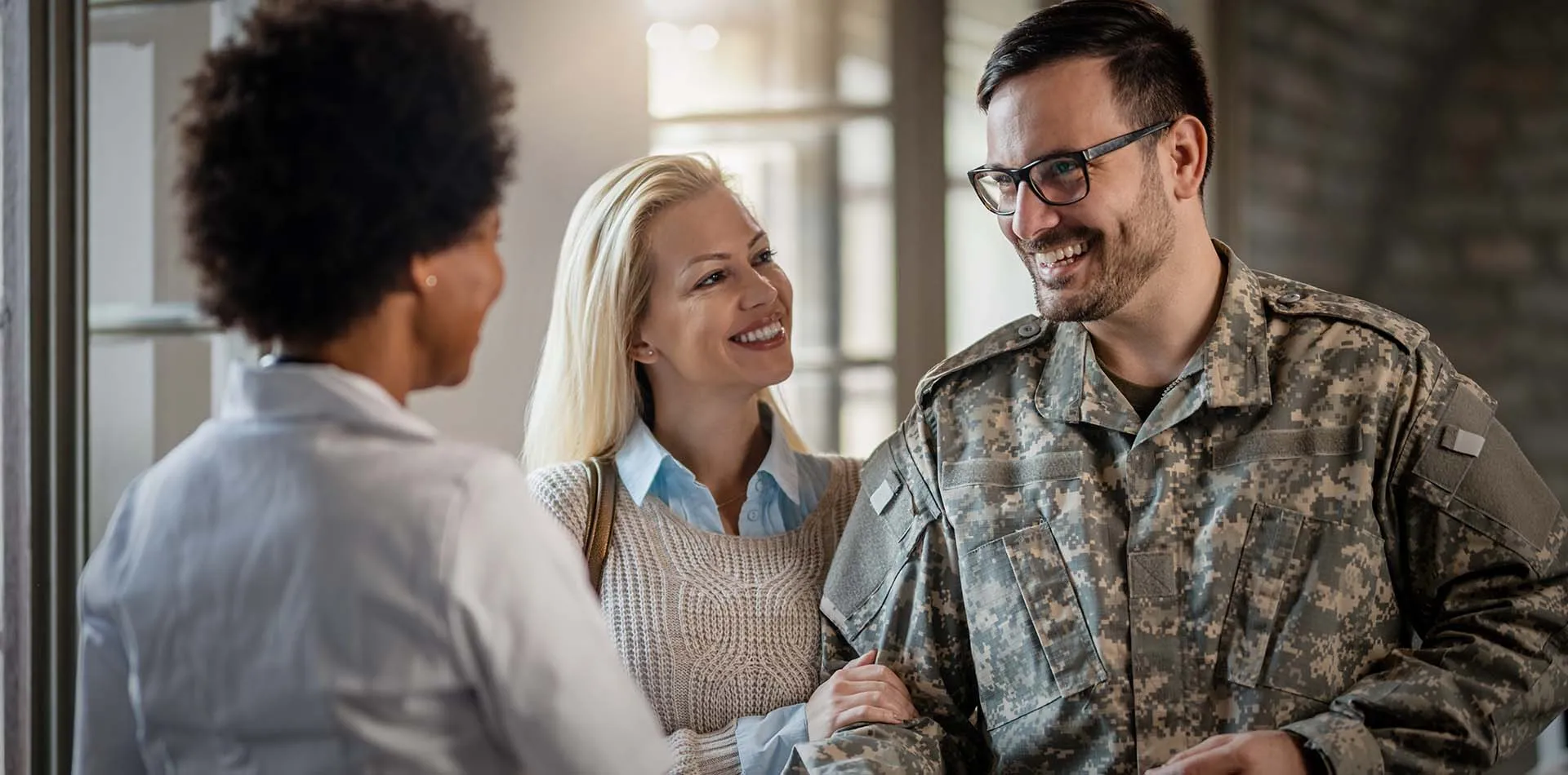 Smiling soldier in camouflage uniform with a woman, talking with a caregiver