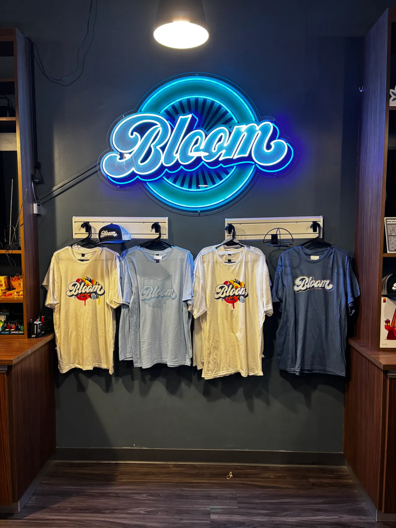 Bloom apparel on the merchandise wall under a neon sign at the West Columbus dispensary.