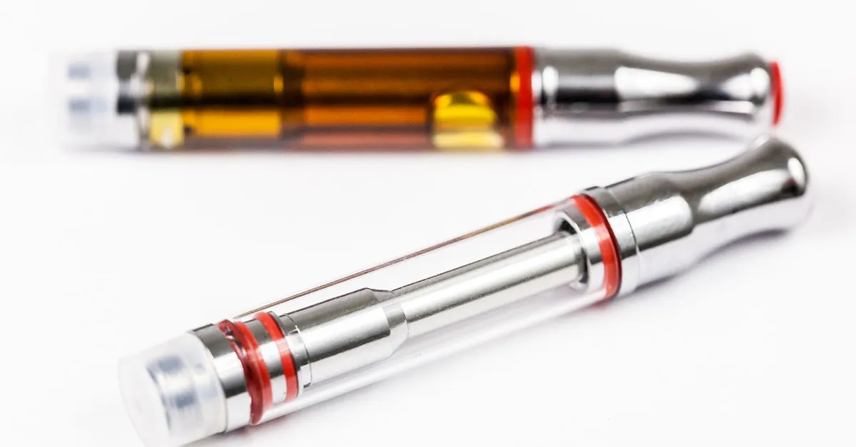 Two glass vape cartridges with red rings, one filled with amber oil and one nearly empty